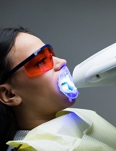 Woman receiving teeth whitening treatment in dental chair