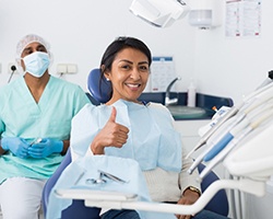 Smiling woman visiting the dentist with thumb up