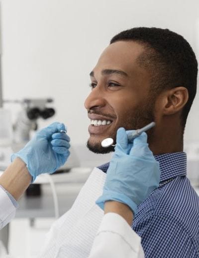 young man sitting in dental chair and smiling at dentist
