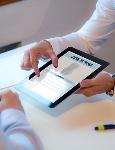 Two people looking at dental insurance form on tablet computer