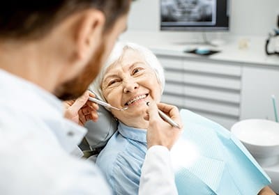 Older woman receiving dental exam after replacing missing teeth
