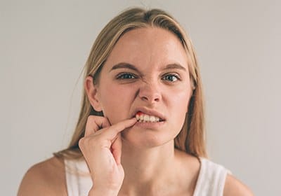 Woman pointing to red spot in her gum tissue before gum disease treatment