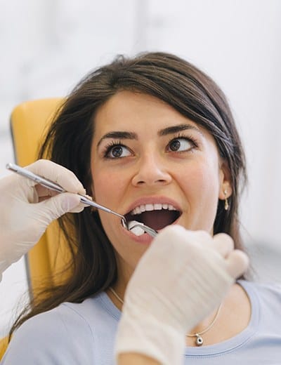 A young female patient having her teeth and gums checked by a dental professional