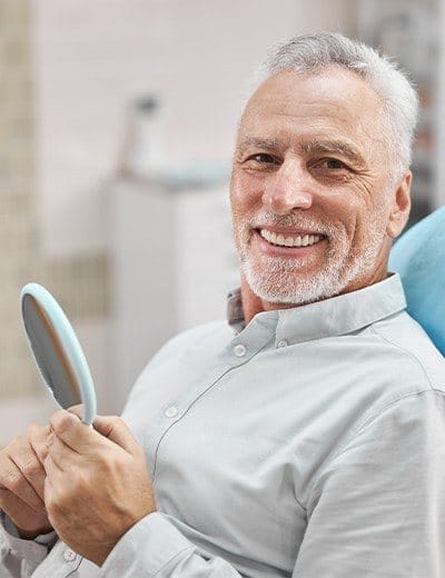 Older man looking at his new veneers with a smile