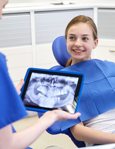 Dentist and teen girl looking at digital x rays of teeth