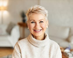 An older woman smiling and pleased with her final dental implant results