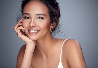 A young woman propping her head up on her hand and smiling after a dental checkup in North Dallas