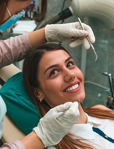 A dental hygienist preparing to clean a female patient’s teeth