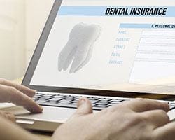 Person filling out a dental insurance form on a laptop