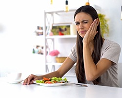 Woman with toothache eating a salad