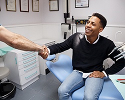 Patient shaking hands with their dentist while seated