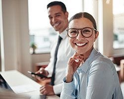 Woman with glasses smiling at a desk
