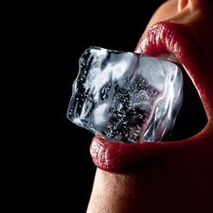 Close up of person with ice cube between their teeth