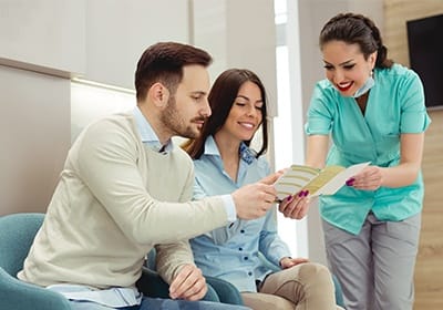 Man and woman talking to dental team member about dental insurance in North Dallas