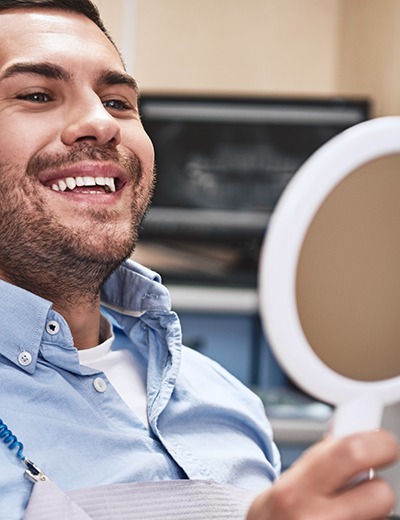 a patient admiring his smile in a mirror