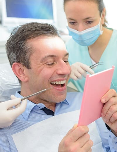A middle aged man looking at his healthier smile after undergoing gum disease treatment