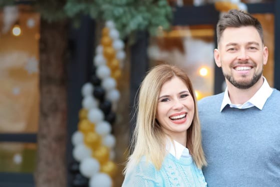 Man and woman smiling together with a restaurant in the background