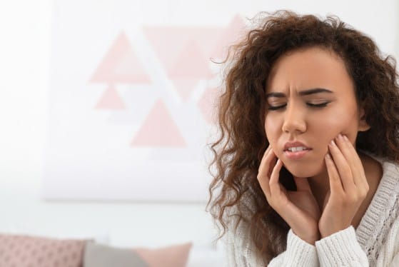 Woman holding her face in pain