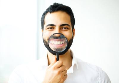 man with magnifying glass in front of his smile