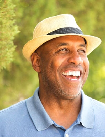 older man in blue shirt smiling in the forest