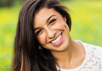 Woman grinning outdoors after teeth whitening in North Dallas