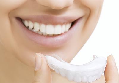 Woman holding teeth whitening tray near her teeth