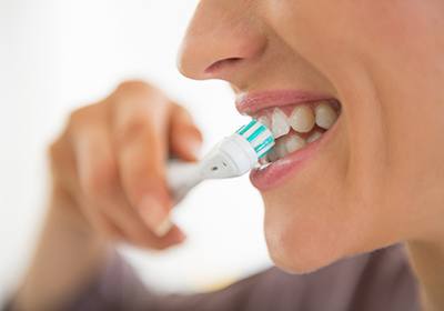 Close up of woman smiling while brushing her teeth