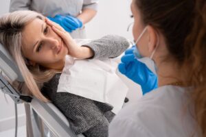 woman holding her cheek experiencing a dental emergency